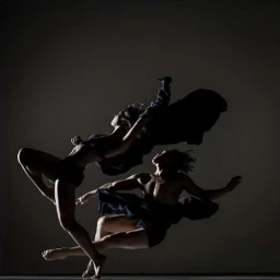 Two dancers in silhouette captured mid-air against a dark gradient studio background with dramatic rim lighting.