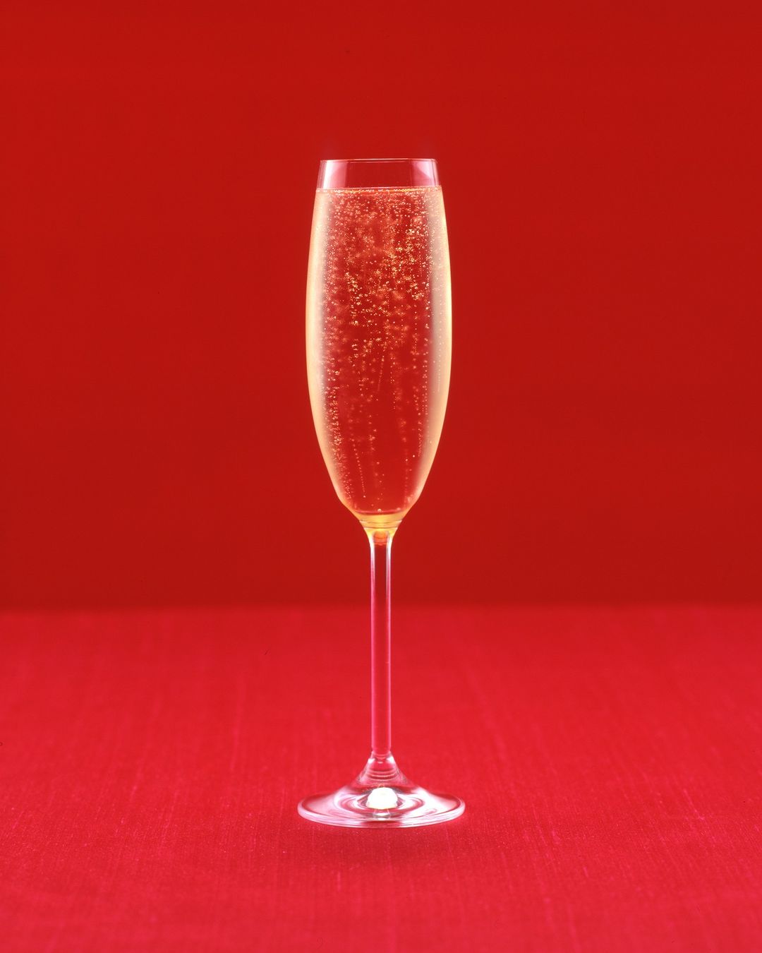 Elegant champagne flute filled with sparkling bubbly against a vibrant red backdrop, ideal for celebrations and festive occasions.