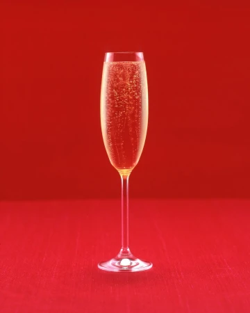 Elegant champagne flute filled with sparkling bubbly against a vibrant red backdrop, ideal for celebrations and festive occasions.
