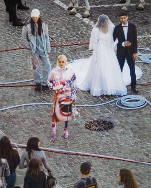 Outdoor fashion shoot features three models: one in white bridal wear, another in patterned streetwear, and another in light blue.  
