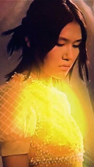 Portrait of a young Asian woman with dark hair, wearing a beaded top with a luminous effect. Beauty and fashion photography.