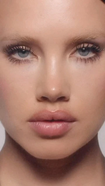 Close-up shot of a fair-skinned adult female model with light blonde hair and light blue eyes, wearing neutral makeup.