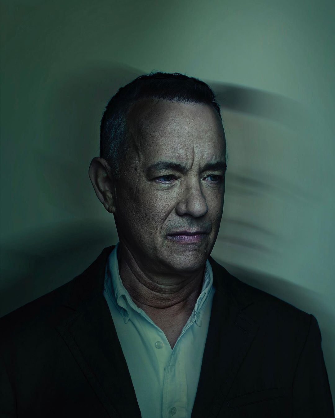 Portrait of adult man in a suit with a serious facial expression, captured in a studio with soft lighting and a blurred background.