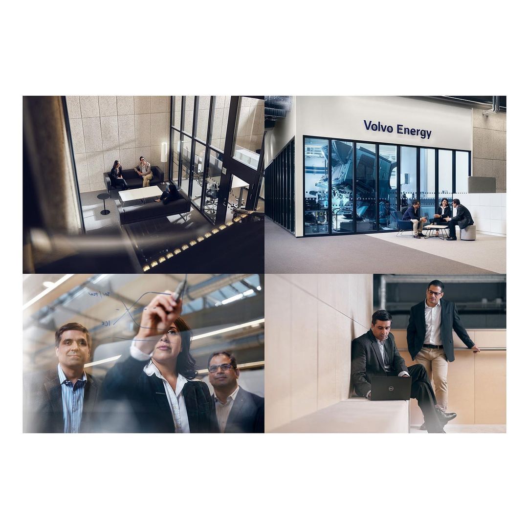 Business meeting in a modern office with people in suits discussing ideas and plans near Volvo Energy signage.