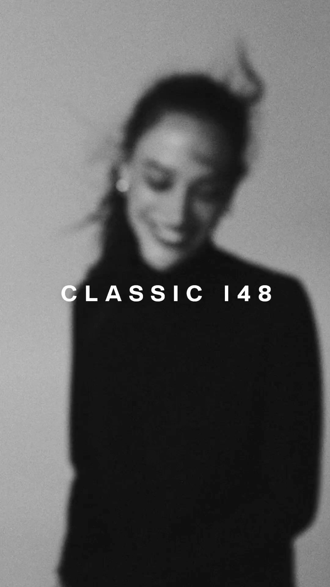 A blurred black and white portrait of a smiling adult woman with dark hair, wearing a dark top, with 'CLASSIC 148' text overlay.