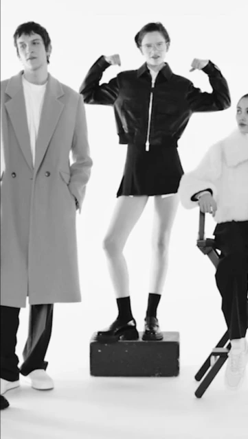 Black and white fashion shot featuring three stylish adults in a minimalist studio setting, showcasing contemporary clothing and posing. 