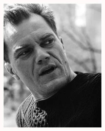 Close-up monochrome portrait of Michael Shannon wearing a dark knitted sweater against an out-of-focus background