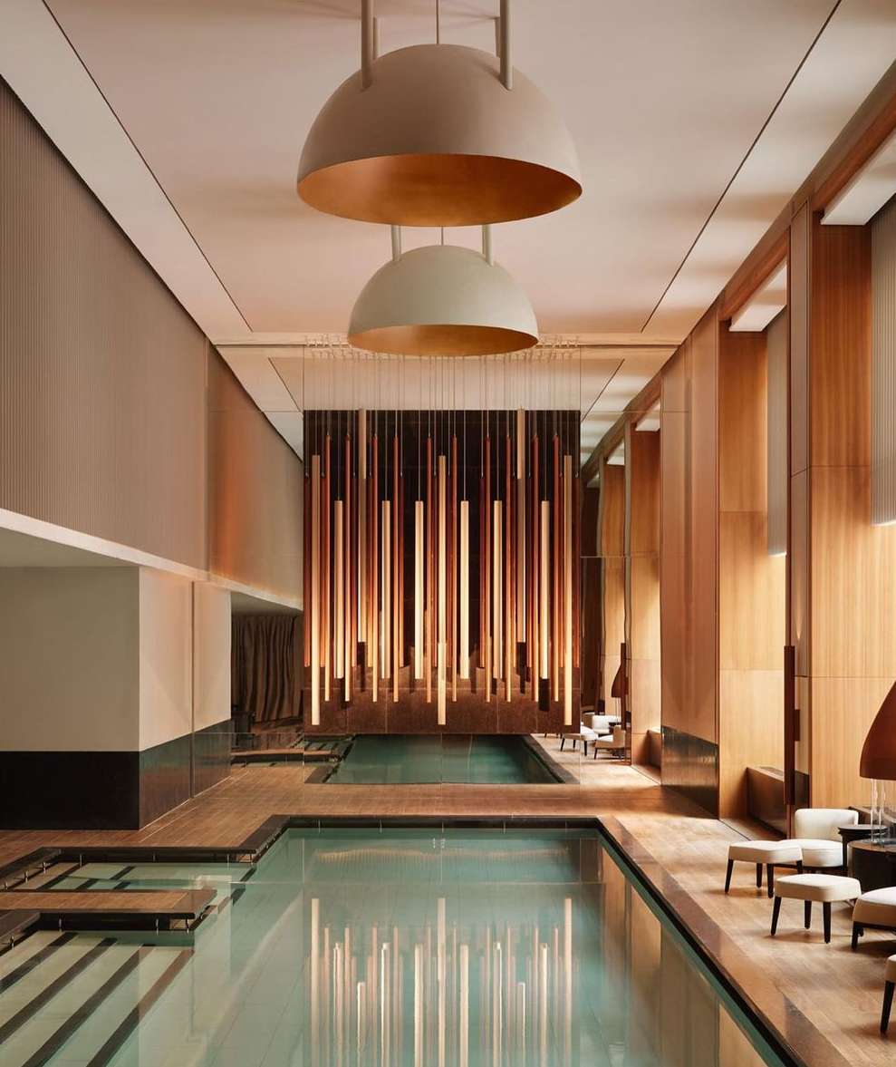 Indoor swimming pool area featuring elegant architectural design, ambient lighting, and minimalist furniture, creating a tranquil and luxurious atmosphere.