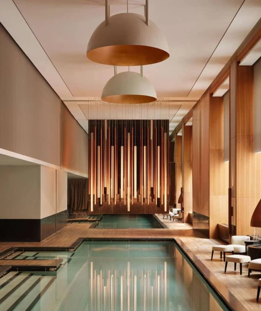 Indoor swimming pool area featuring elegant architectural design, ambient lighting, and minimalist furniture, creating a tranquil and luxurious atmosphere.