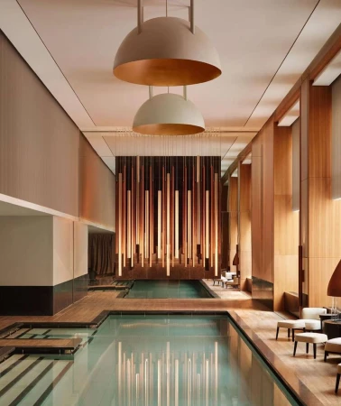 Indoor swimming pool area featuring elegant architectural design, ambient lighting, and minimalist furniture, creating a tranquil and luxurious atmosphere.