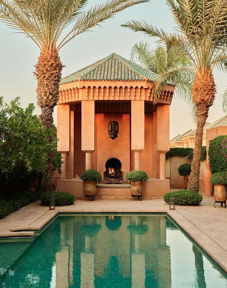 Tranquil turquoise swimming pool with terracotta pavilion and lush palm trees, evoking a serene resort atmosphere in a luxury setting.