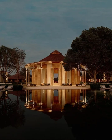 Exterior of a modern building with a brown roof reflecting in a dark pool of water surrounded by trees at twilight.