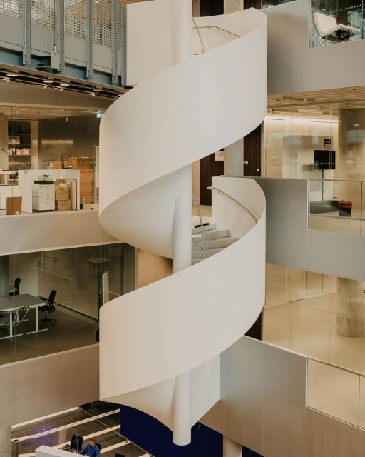 Interior view of a modern architectural design featuring a white spiral staircase in a multi-level office with neutral colour palette.