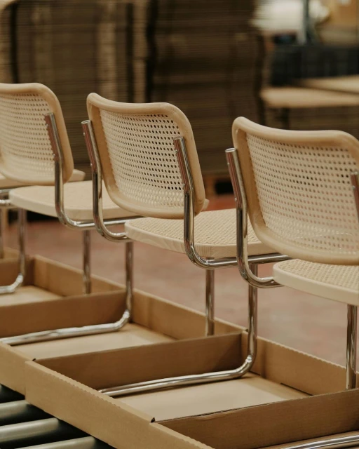 Assembly line with light wood chairs in a production facility, showcasing minimalist furniture design and manufacturing.