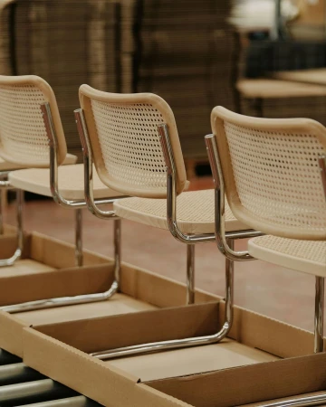 Assembly line with light wood chairs in a production facility, showcasing minimalist furniture design and manufacturing.