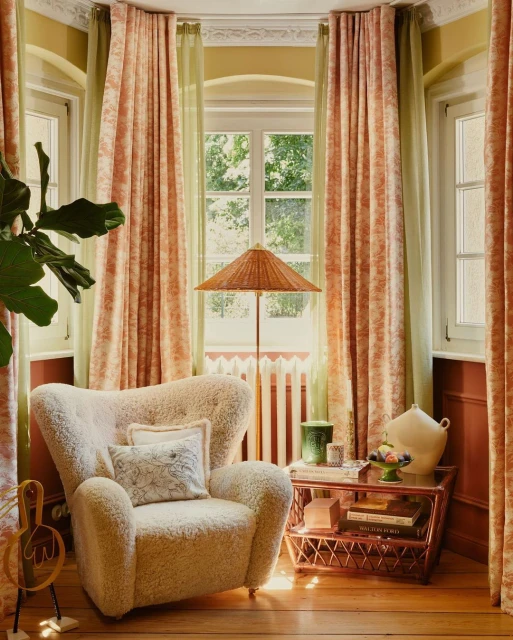 Comfortable armchair in a cozy living room with warm lighting and decorative accents, including curtains, a lamp, and a side table.