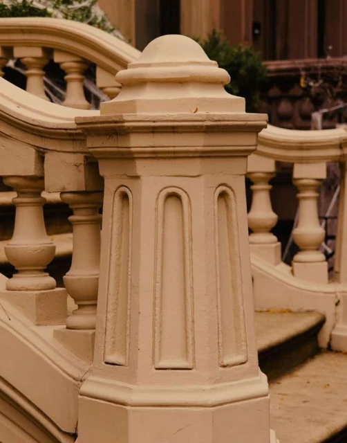 Exterior architectural detail features a cream-colored stone balustrade post with molded details and rounded top against a building.