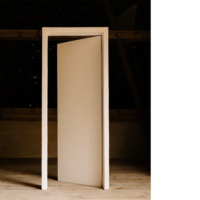 Open door in a dimly lit attic room with wooden beams and floorboards, creating a sense of mystery and anticipation.