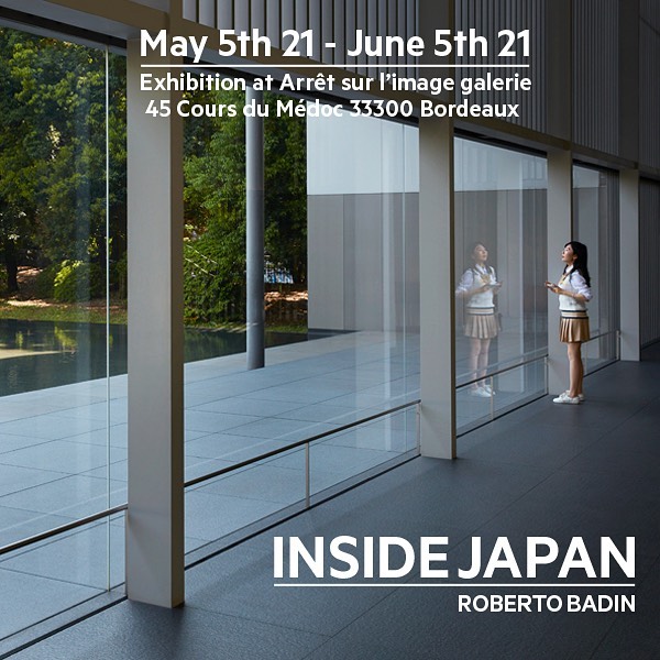 Exhibition poster showcasing a girl in Japanese school uniform standing inside modern architecture against a window view of greenery.