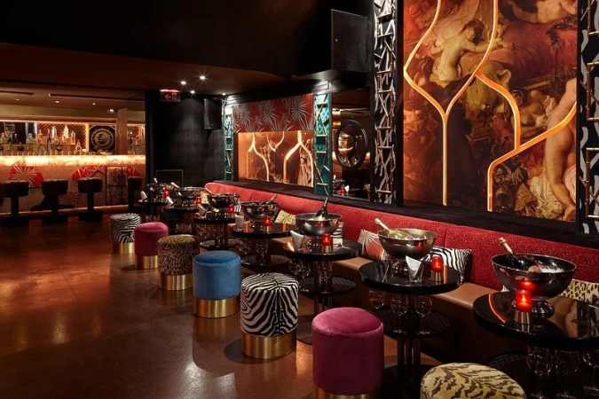 Luxurious bar interior featuring velvet seating, round tables with champagne, and decorative lighting, creating a sophisticated atmosphere.