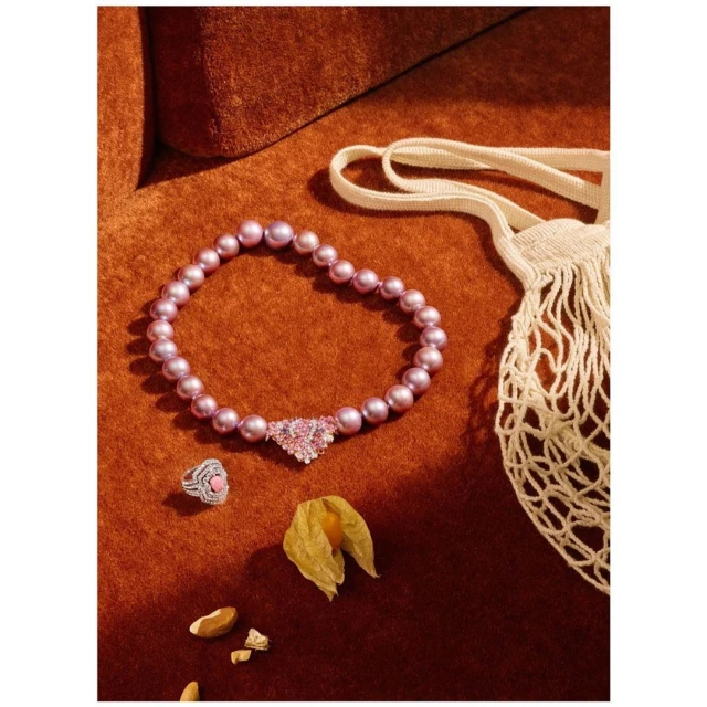 Elegant jewelry flat lay on warm brown fabric featuring a pearl necklace, diamond ring, and decorative ground cherry.