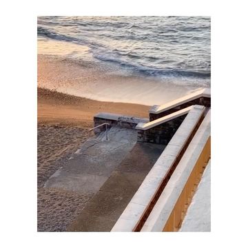 Scenic beach stairs lead to the ocean waters in this serene coastal landscape with sand and handrails.