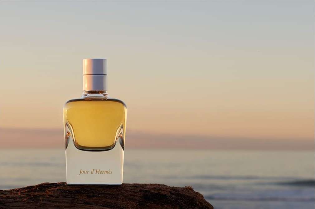Hermès Jour d'Hermès perfume bottle on a rock with the ocean and horizon in the background during golden hour for a beauty shot.