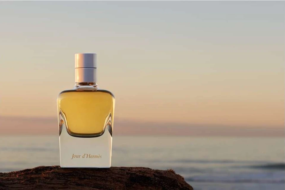 Hermès Jour d'Hermès perfume bottle on a rock with the ocean and horizon in the background during golden hour for a beauty shot.