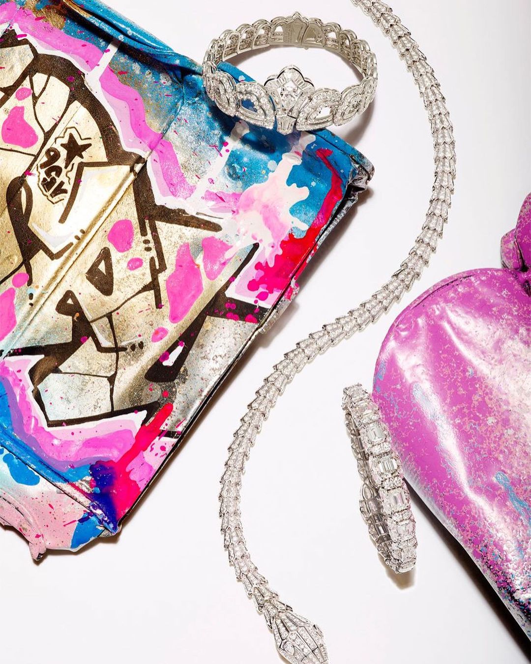 Diamond jewelry set including a bracelet, choker, and necklace displayed with a colorful handbag against a bright, white background.