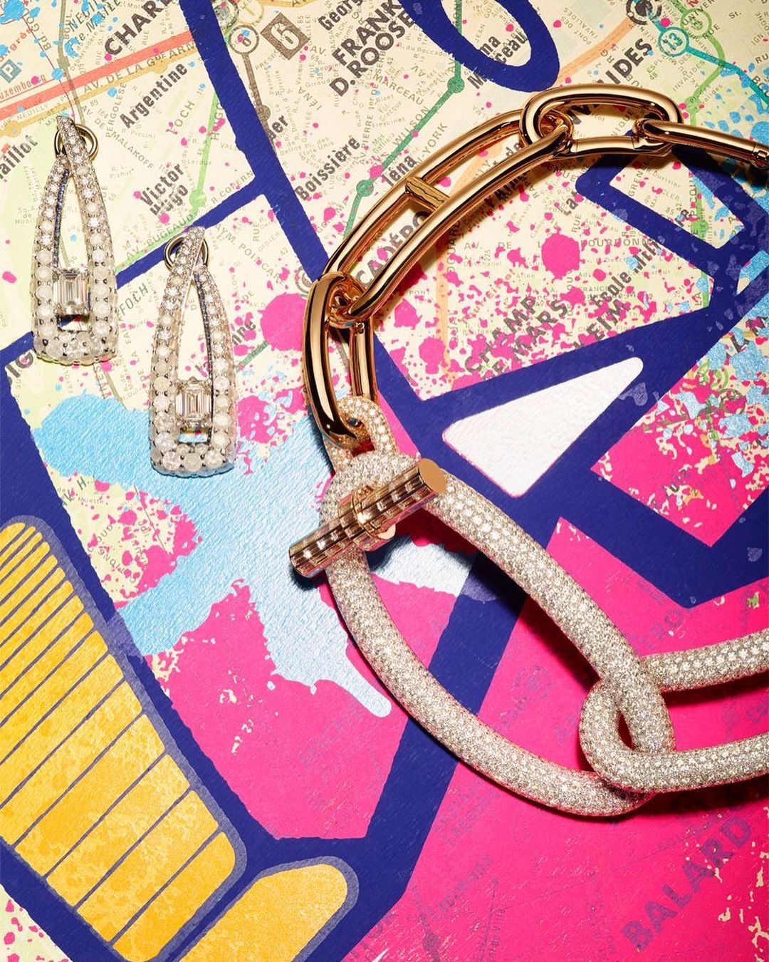 Earrings and a necklace with gemstones are arranged against a colorful map background for a product shot in a jewelry advertisement.