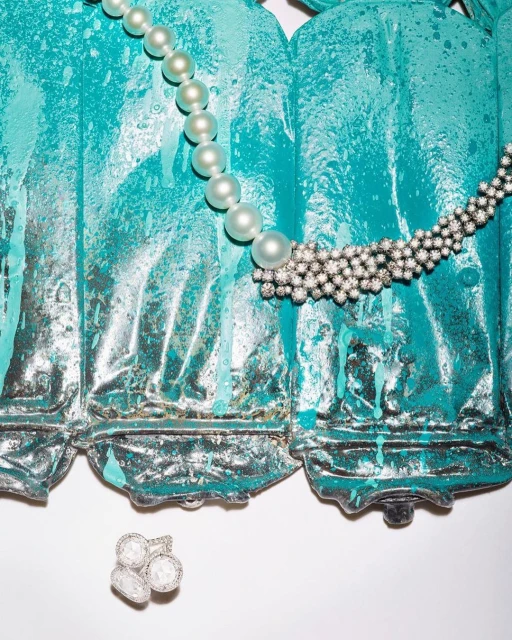 Elegant pearl necklace and diamond jewelry displayed against a textured teal and gray backdrop in a visually appealing still life.