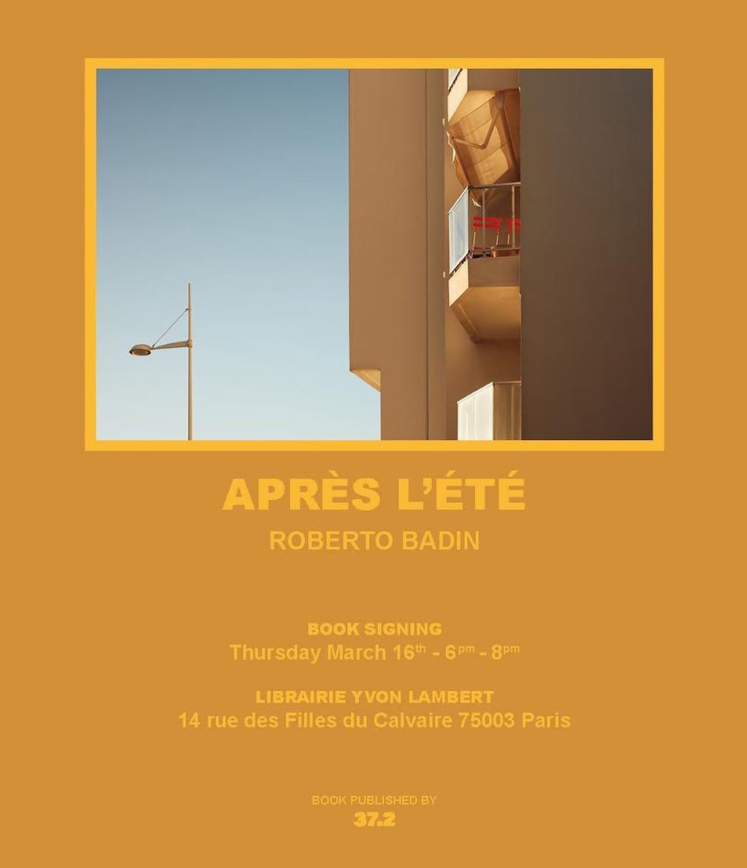 Building facade with open awning and blue sky on mustard-colored background for Roberto Badin book signing event in Paris.