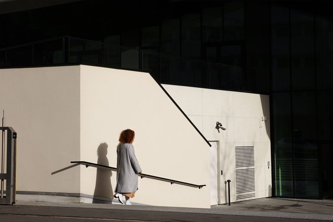 Woman in grey coat walking up exterior stairs in Paris captured by photographer Roberto Badin