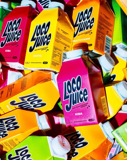 Pile of colorful Loco Juice cartons in red, yellow, orange, green, and pink, creating a vibrant and refreshing visual display.