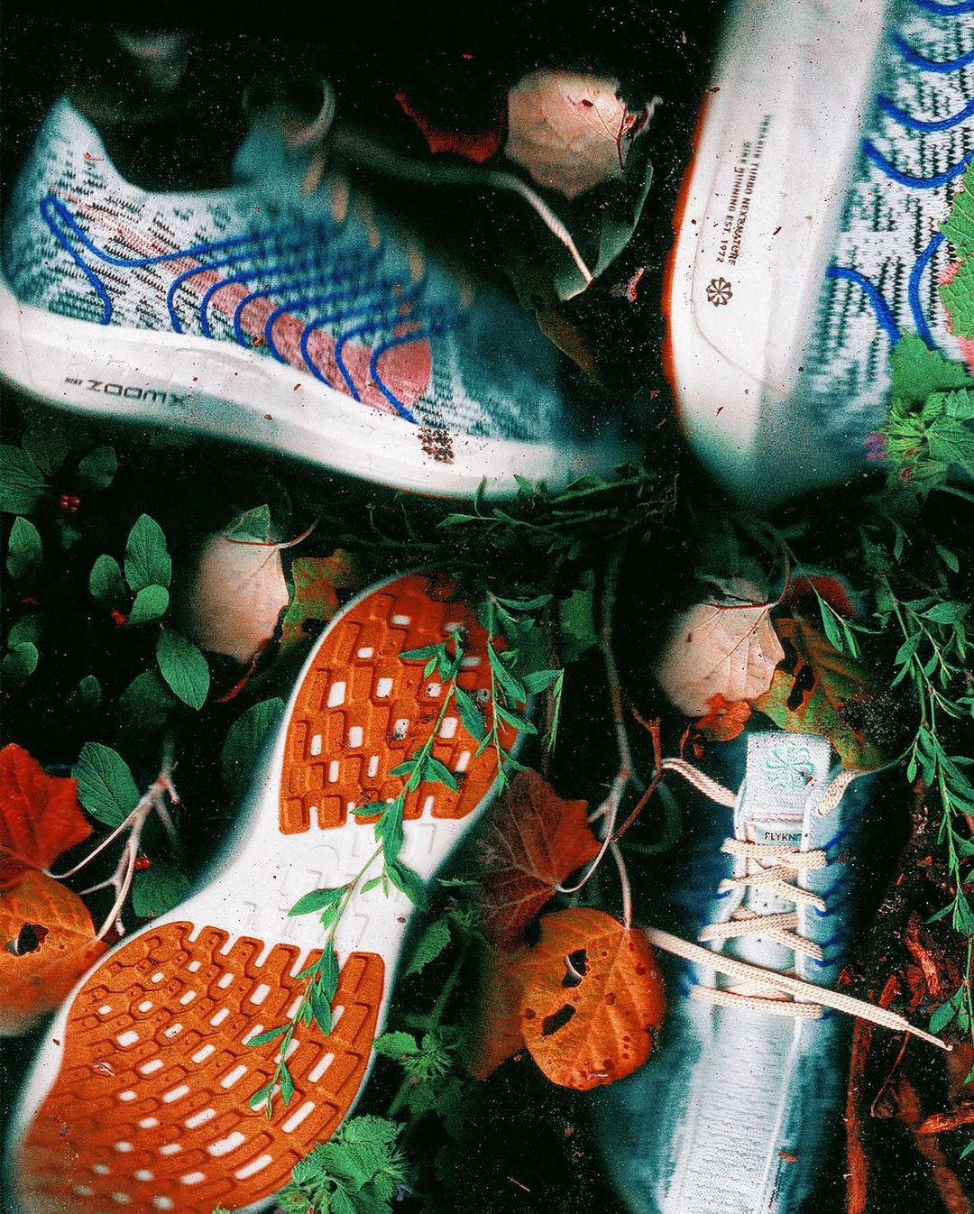 Eye-level view showcases three Nike running shoes entangled with greenery and fallen leaves. The shoes exhibit detailed designs.