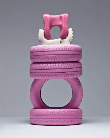 Tower of pink car tires and a pink-and-white neck pillow are vertically stacked against a grey background in a studio shot.