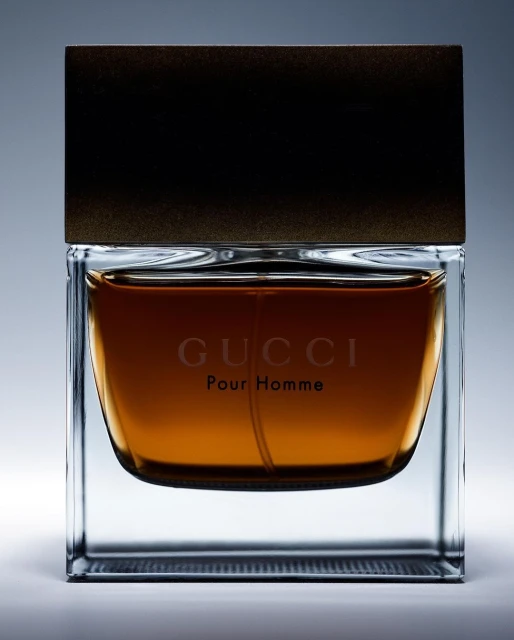 Elegant product shot of a glass bottle of Gucci Pour Homme cologne with a dark brown cap, centered on a pale gray background.