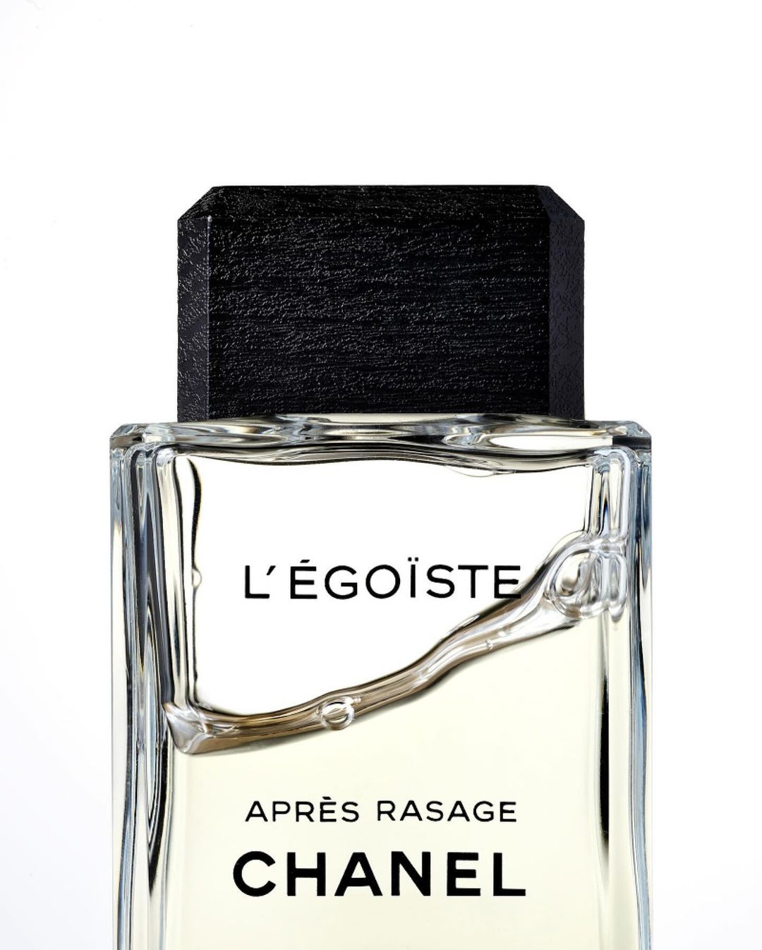 Close-up shot of Chanel L'Égoïste Après Rasage bottle with a black cap against a white background in a studio setting.
