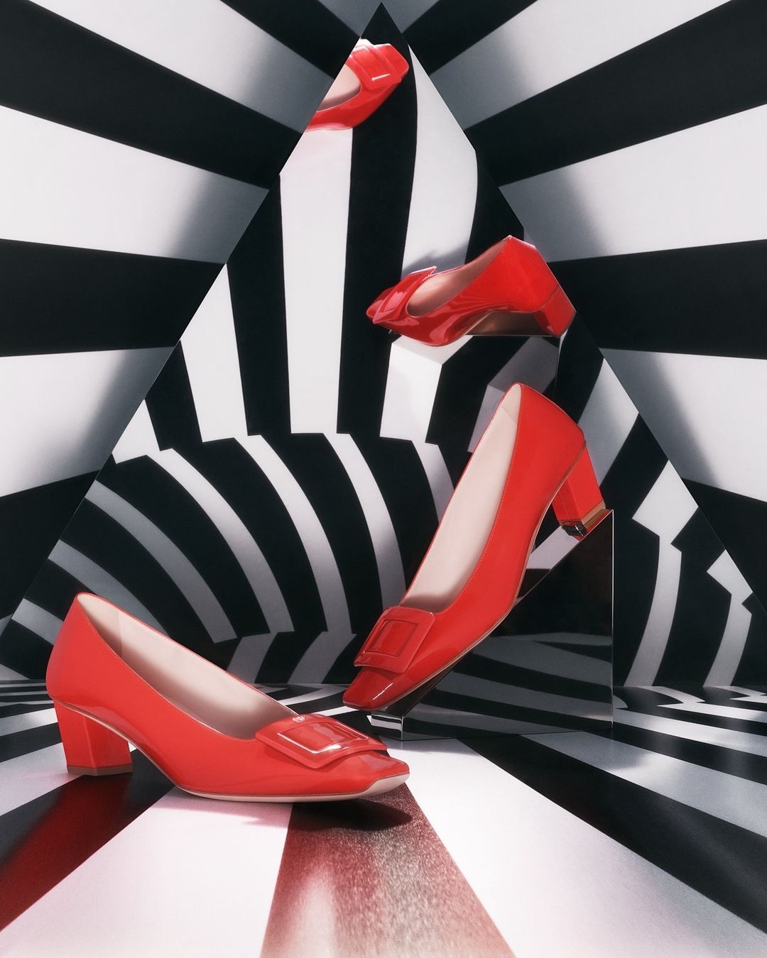 Red high heel shoes displayed against a black and white striped background, creating a visually striking composition for fashion.