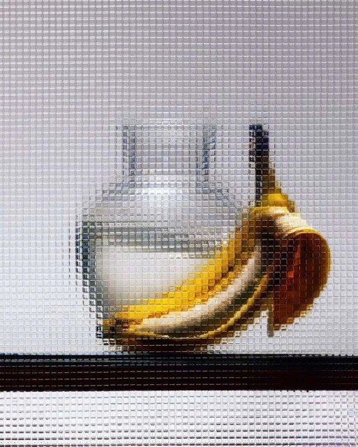 Still life photograph of a glass vase with water and a ripe banana against a textured, pixelated background.