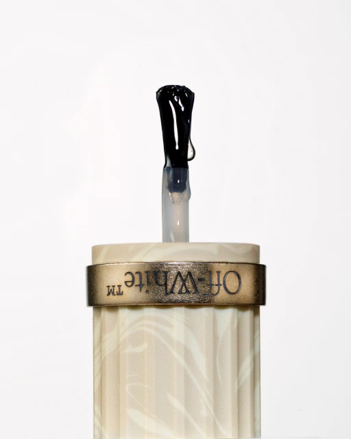 Close-up studio shot of an Off-White nail polish applicator with a black brush, set against a clean white backdrop, product presentation.