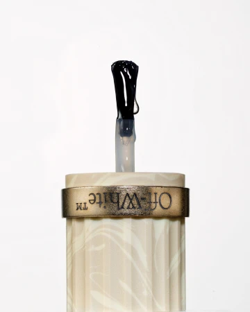 Close-up studio shot of an Off-White nail polish applicator with a black brush, set against a clean white backdrop, product presentation.