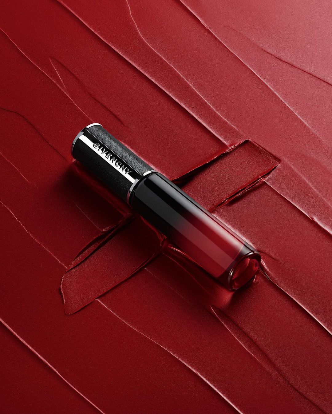 Givenchy lipstick product shot. The lipstick, in packaging, is placed on a background of smeared red lipstick for a beauty advertisement.
