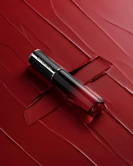 Givenchy lipstick product shot. The lipstick, in packaging, is placed on a background of smeared red lipstick for a beauty advertisement.