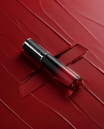 Givenchy lipstick product shot. The lipstick, in packaging, is placed on a background of smeared red lipstick for a beauty advertisement.
