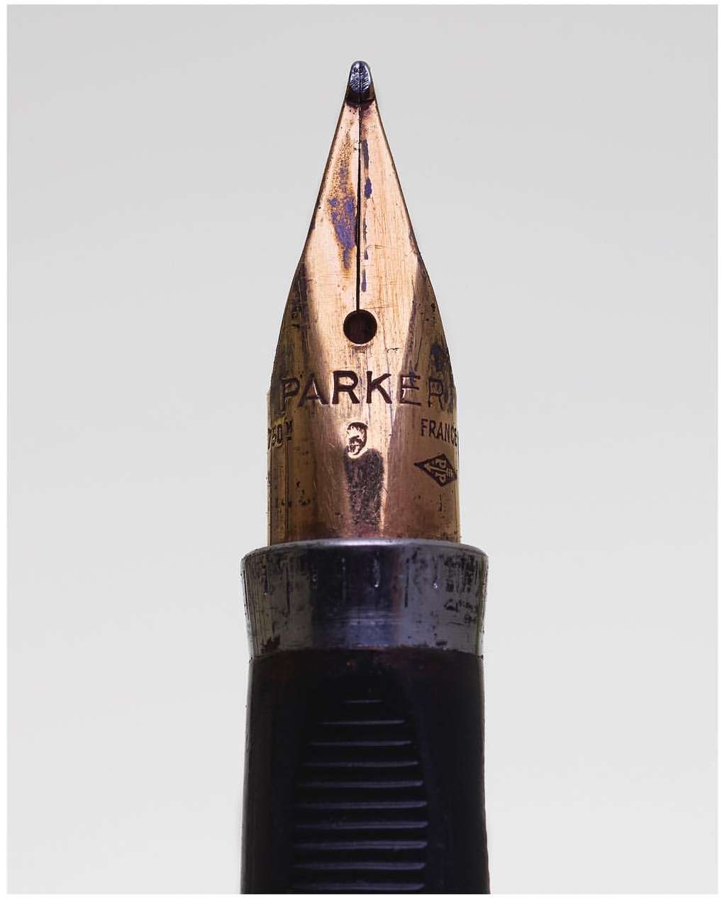 Close-up of a Parker fountain pen nib showing the brand engraving and aged metal against a neutral background in a studio shot.