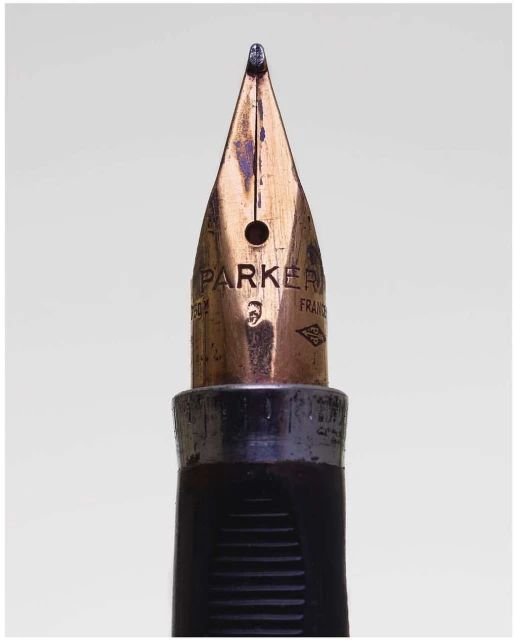 Close-up of a Parker fountain pen nib showing the brand engraving and aged metal against a neutral background in a studio shot.
