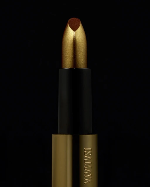 Close-up of gold and black lipstick tube on black background, beauty product advertisement with metallic textures.