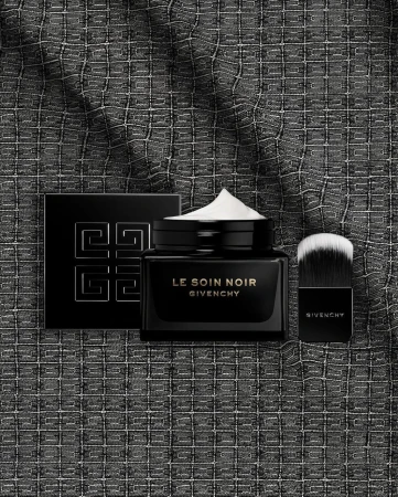 Luxury Givenchy skincare products on a textured dark background. The set includes cream, powder, and a makeup brush for beauty application.