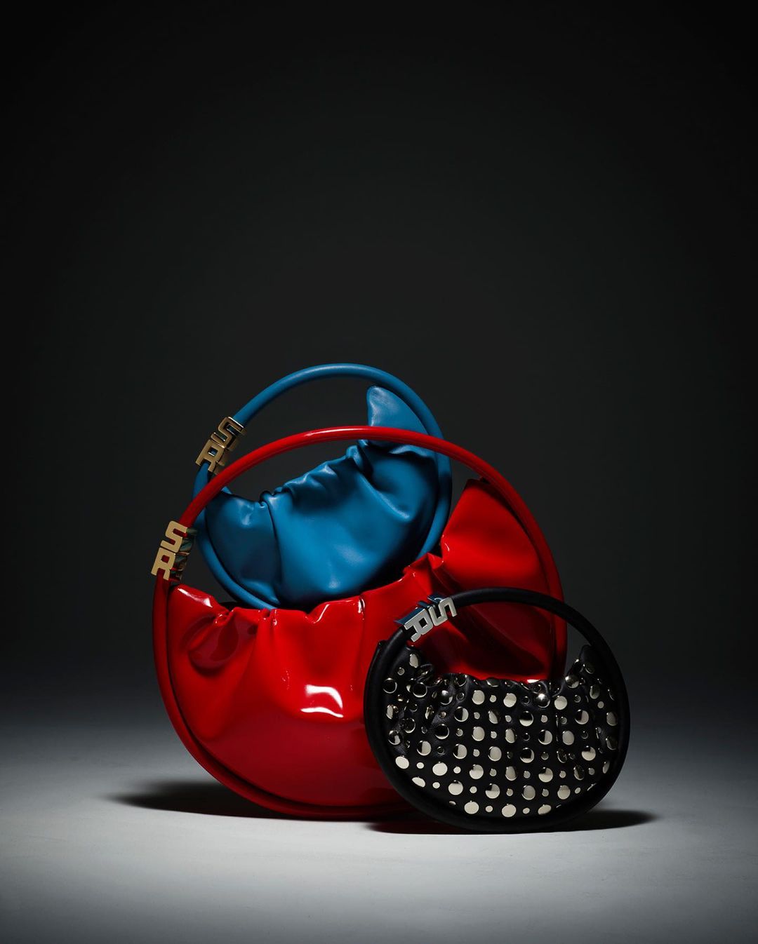 Three round handbags are arranged together in a studio setting with a soft spotlight, creating a minimalist and modern fashion product shot.